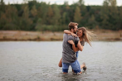 男人拥抱笑女人站在水里 · 免费素材图片