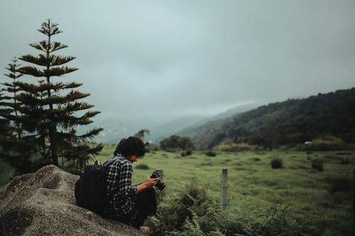 坐在多云的天空下的松树附近的人 · 免费素材图片
