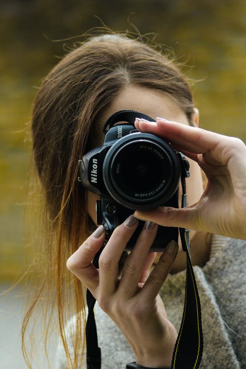 女人使用黑色尼康单反相机的特写摄影 · 免费素材图片