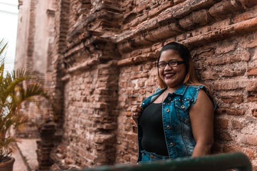 斜倚在棕色砖墙上的女人 · 免费素材图片