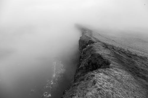 悬崖在水体附近的灰度照片 · 免费素材图片