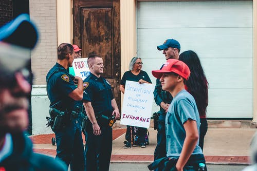 警察站在女人和男人附近举起标牌 · 免费素材图片