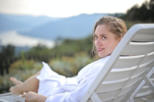 躺在泳池椅上的微笑女人穿着白色浴袍的选择性聚焦摄影 · 免费素材图片