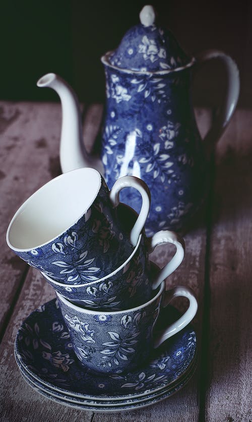 蓝色和白色的花卉陶瓷茶杯和棕色木制的桌子上的茶壶 · 免费素材图片