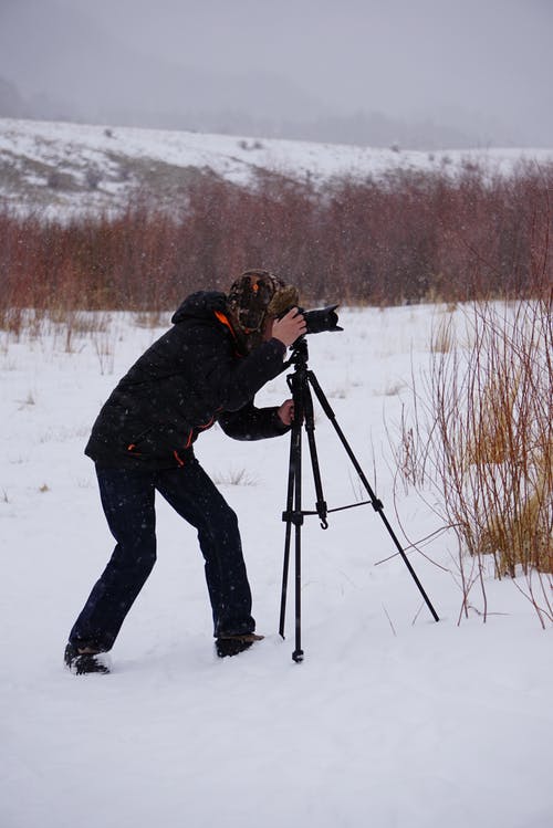 在积雪覆盖的地面中间拍照的人 · 免费素材图片