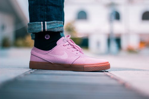 穿着粉红色耐克低帮运动鞋的人的选择性聚焦照片 · 免费素材图片