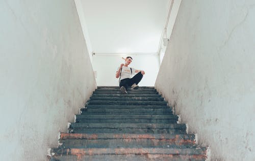 坐在楼梯上的白顶的男人 · 免费素材图片