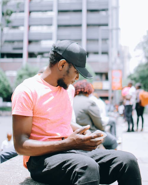 使用手机时坐在灰色的长椅上的人 · 免费素材图片