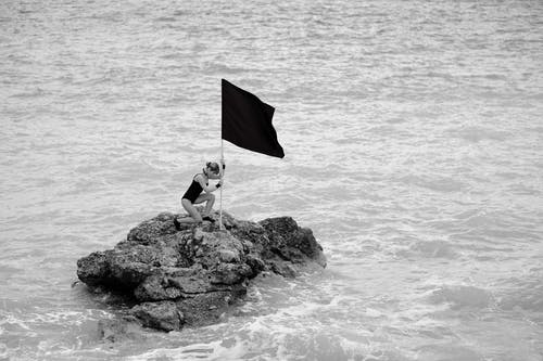 拿着旗帜的岩层上的女人 · 免费素材图片