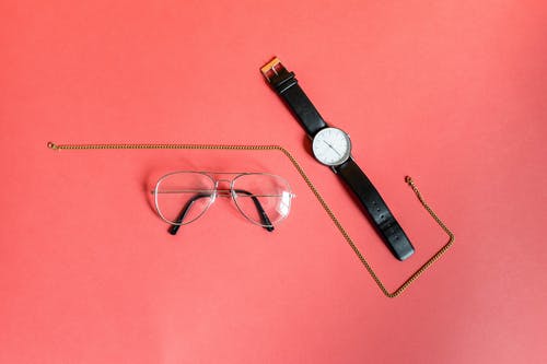 模拟手表和粉红色表面眼镜之间的金色项链 · 免费素材图片