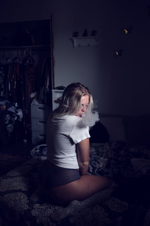 女人穿着白衬衫坐在沙发上和吸烟 · 免费素材图片