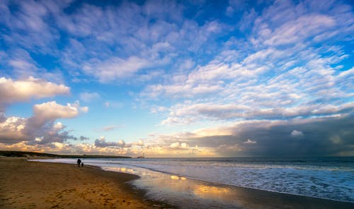 在海滩上在岸上行走的人 · 免费素材图片