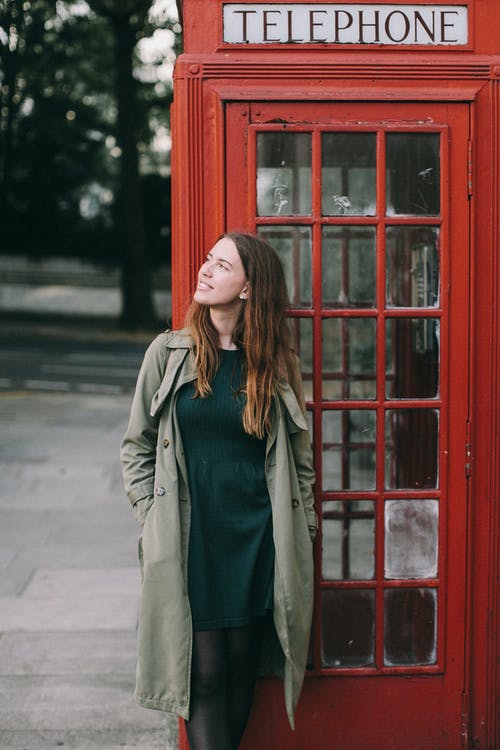 一个女人站在电话亭前的照片 · 免费素材图片