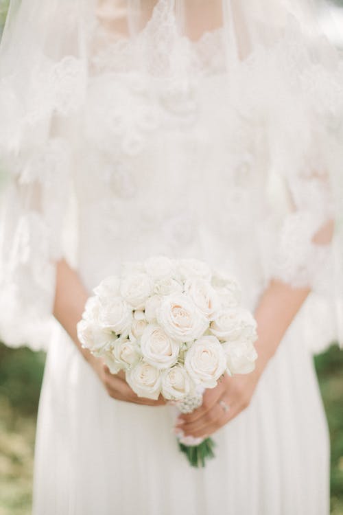 拿着花束时穿白色婚纱的女人 · 免费素材图片