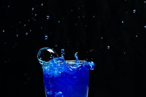 蓝色液体溅在玻璃上 · 免费素材图片