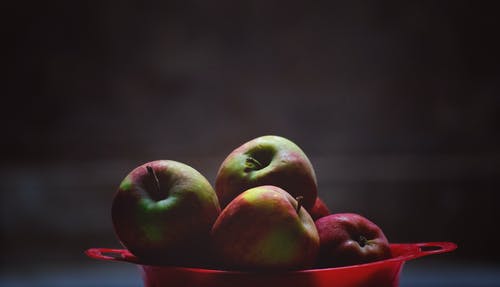 红色塑料碗里的绿色和红色苹果果实 · 免费素材图片