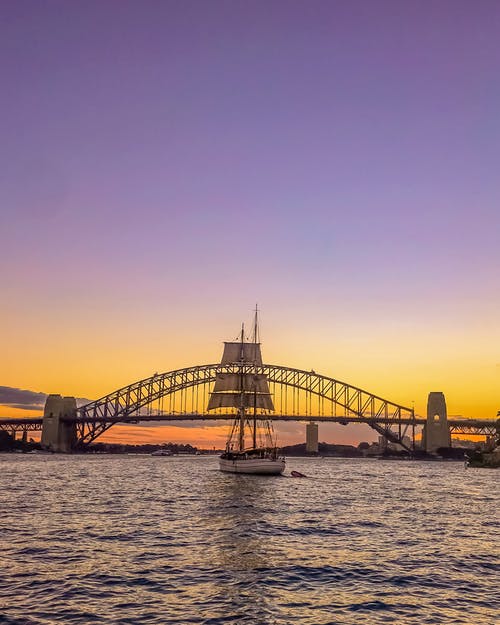 帆船在橙色夕阳下桥前 · 免费素材图片