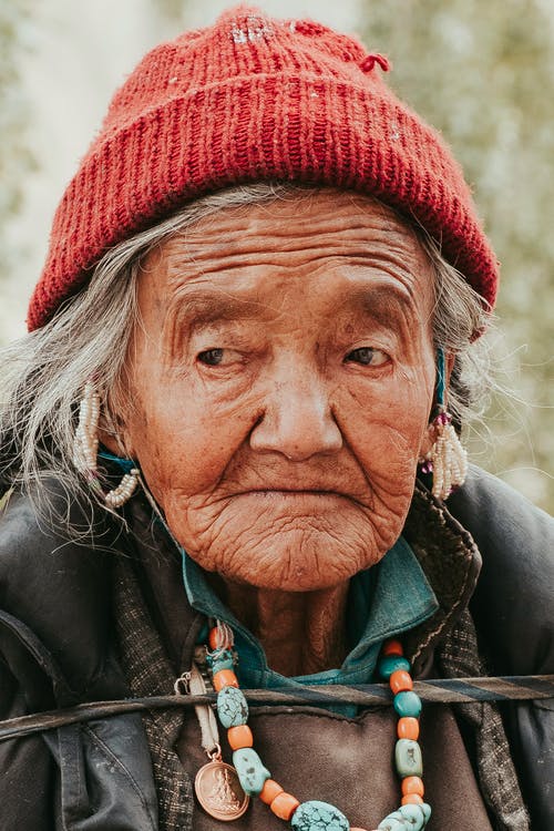 一个老女人，戴着红色的针织帽的特写照片 · 免费素材图片