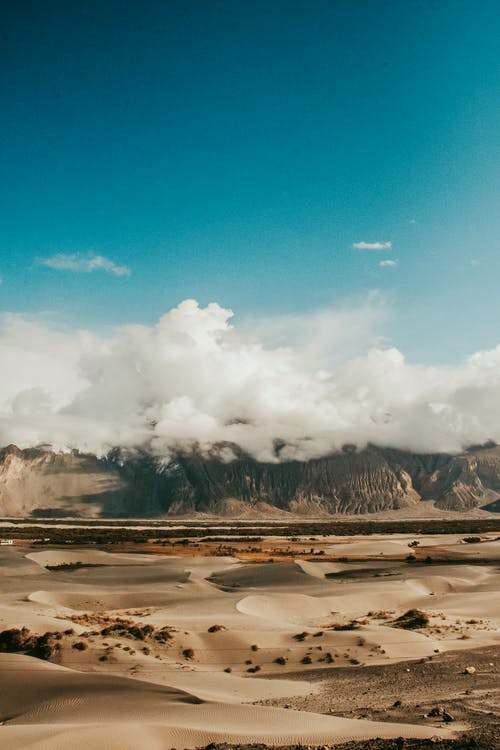 在荒芜的土地上覆盖着云层的山 · 免费素材图片