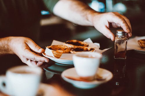 男子手持碗糕点和调味品容器的选择性聚焦摄影 · 免费素材图片