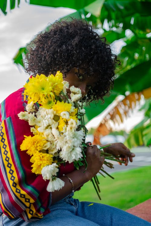 女孩捧着白色和黄色的花瓣花 · 免费素材图片