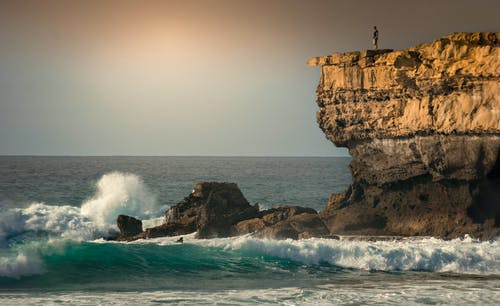 站在被海包围的岩层上的人 · 免费素材图片