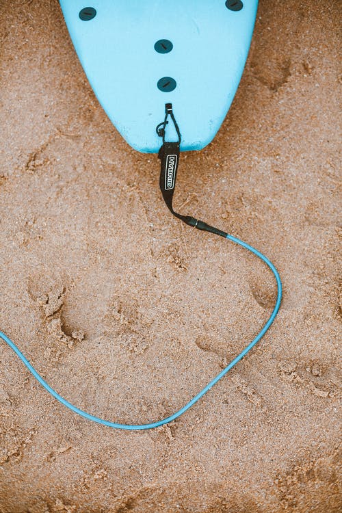 蓝色的冲浪板，用皮带绑在沙滩上的照片 · 免费素材图片