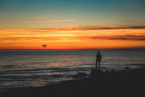 人站在海边岩石上的剪影 · 免费素材图片