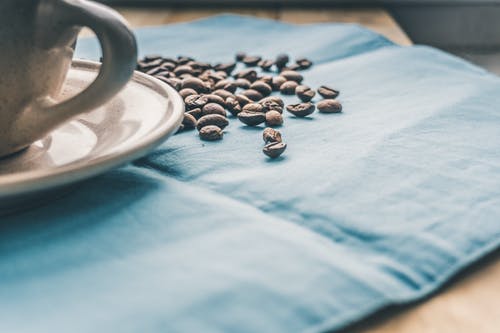 蓝色纺织上的黑咖啡豆 · 免费素材图片