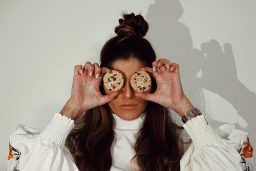 女人覆盖着两个巧克力饼干的眼睛 · 免费素材图片