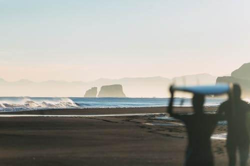 人在海边举行冲浪板的剪影 · 免费素材图片