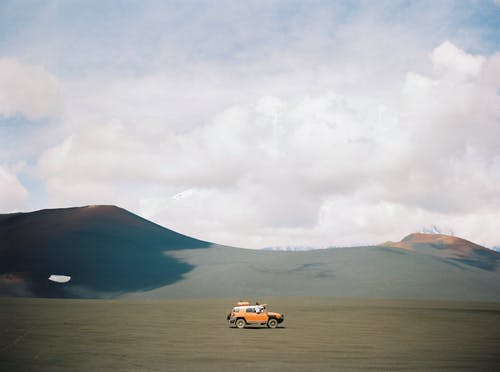 在棕沙上的橙色车辆 · 免费素材图片