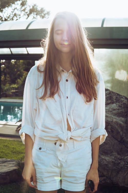 女人穿着白色纽扣式长袖衬衫和白色短裤站在游泳池附近 · 免费素材图片