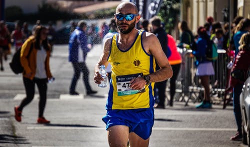 黄色和蓝色背心跑步的人 · 免费素材图片