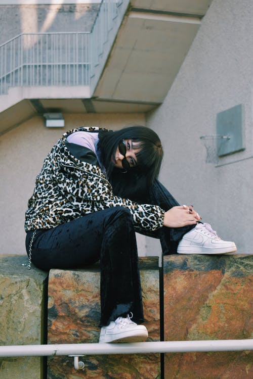 女人坐在棕色的石头上 · 免费素材图片