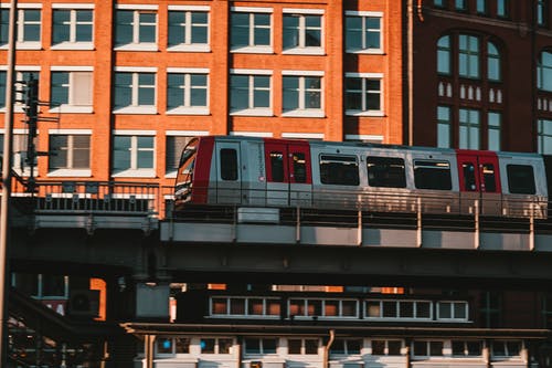 棕色混凝土建筑附近的白色和红色火车 · 免费素材图片
