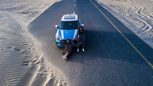 蓝色车辆前的两个女人 · 免费素材图片