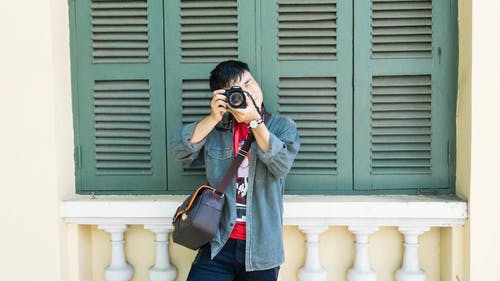 男子用单反相机拍照 · 免费素材图片