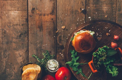 汉堡和蔬菜放在棕色的木质表面 · 免费素材图片