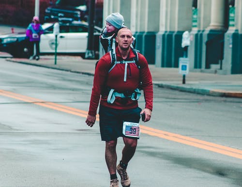 在建筑物附近行走时背着婴儿的人 · 免费素材图片