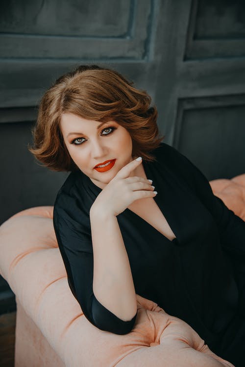 女人坐在粉红色的床上 · 免费素材图片