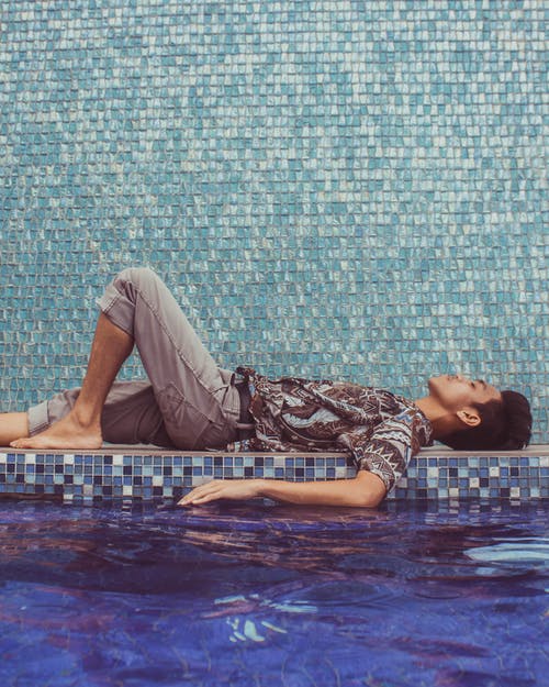 男子躺在游泳池边 · 免费素材图片