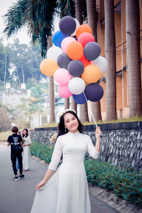 女人拿着气球捆绑穿着白色的衣服 · 免费素材图片