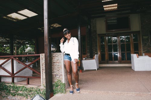 站在扶手旁边的白色礼服衬衫的女人的照片 · 免费素材图片