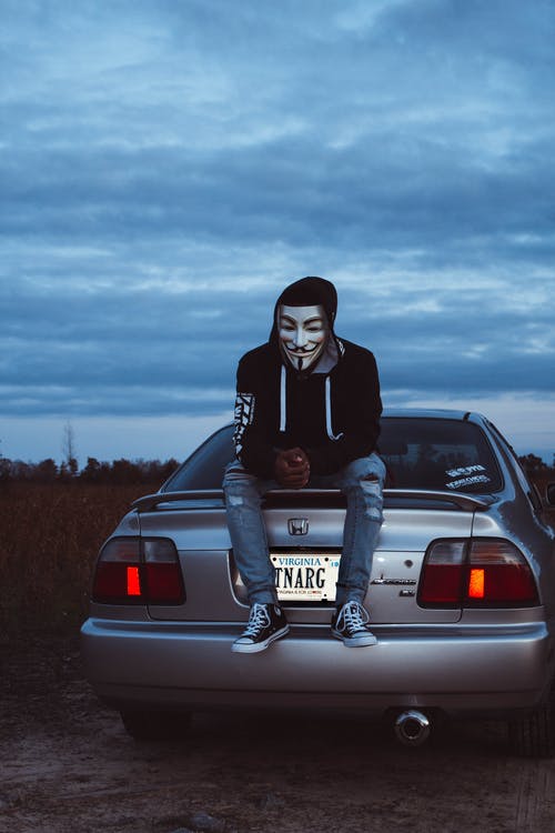 男子戴着盖伊·福克斯面具坐在灰色的本田车上 · 免费素材图片