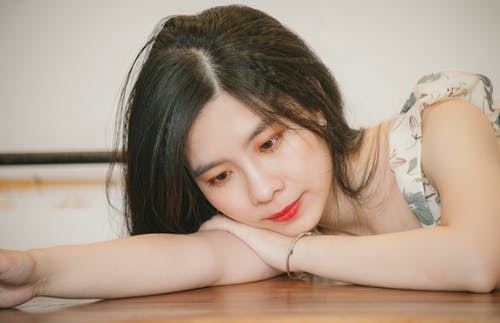 女人靠在棕色的桌子上 · 免费素材图片
