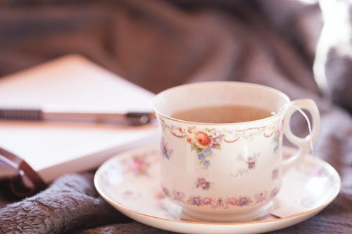在装有咖啡的茶碟上的白色和五彩花卉陶瓷茶杯的选择性聚焦摄影 · 免费素材图片