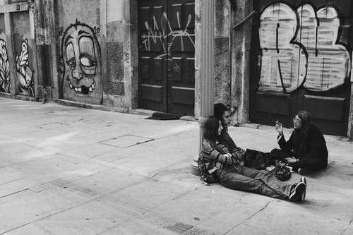 人坐在混凝土路面上的灰度摄影 · 免费素材图片