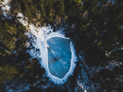 树木包围的积雪水域航拍 · 免费素材图片