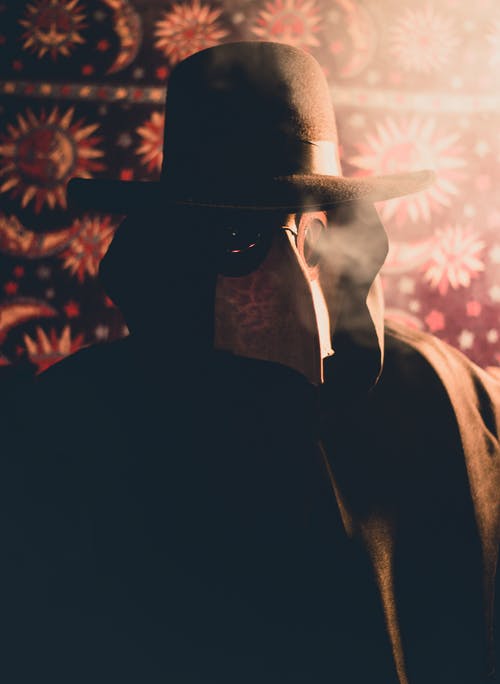 黑大衣和帽子与瘟疫医生面具的人 · 免费素材图片
